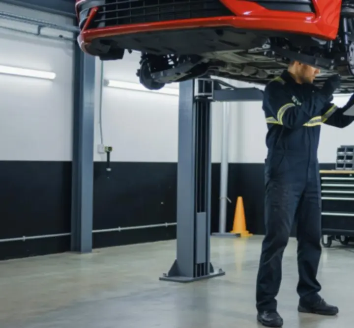 Mechanic performing a suspension inspection on a vehicle raised in a professional workshop